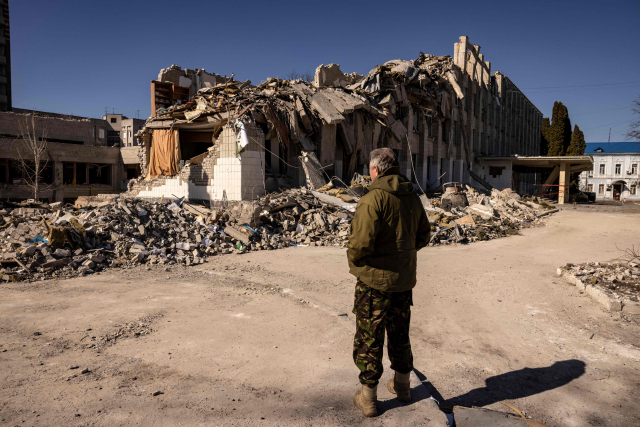 우크라이나 영토방위대 병사가 23일(현지시간) 러시아군의 공격이 집중된 북부 지토미르에서 파괴된 가옥을 바라보고 있다. /연합뉴스