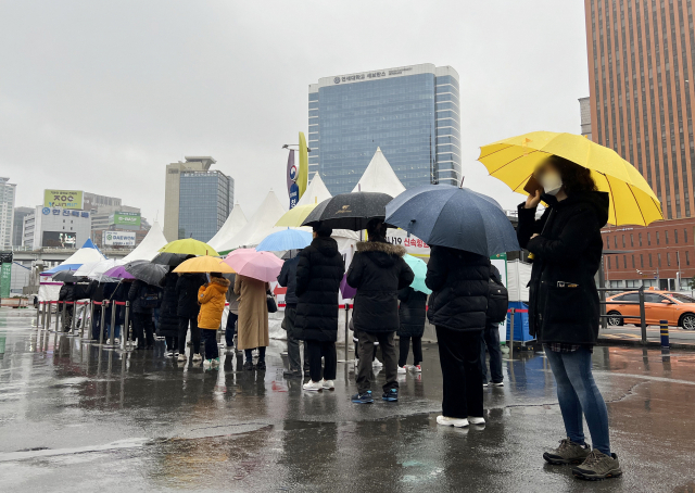 지난 19일 비가 내리는 가운데 서울 중구 서울역 임시 선별검사소에서 우산을 쓴 시민들이 검사를 기다리고 있다. 연합뉴스