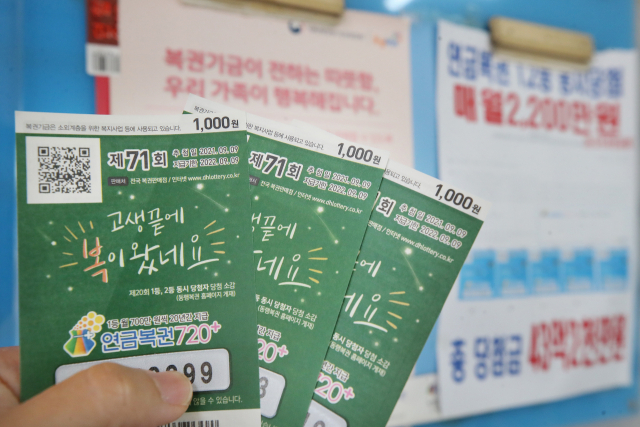 한 시민이 복권판매점에서 연금복권720+를 들어보이고 있다. 연합뉴스