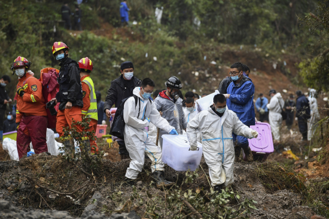 수색 구조대원들이 24일 중국 남부 광시좡족자치구 중국 동방항공 여객기 추락 현장에서 희생자의 소지품이 들어 있는 것으로 추정되는 상자를 운반하고 있다. 신화연합