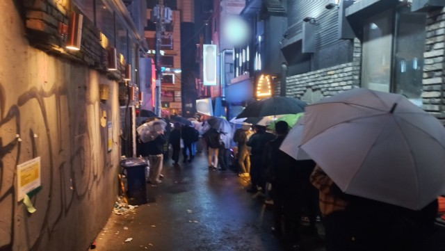 마스크를 턱 밑에 걸친 수십 명이 지난 25일 저녁 서울 마포구 홍대 근처의 좁은 골목 안에 모여 흡연을 하고 있다. 이건율 기자