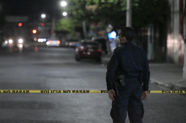 26일(현지시간) 엘살바도르 라리베르타드에서 한 경찰관이 갱단에 의한 살인사건 현장을 지키고있다. AFP연합뉴스