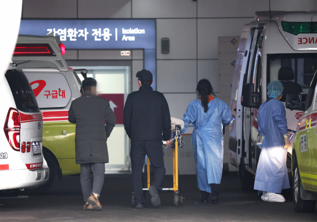 25일 오후 서울 중랑구 서울의료원에서 의료진이 코로나19 환자를 옮기고 있다. 연합뉴스
