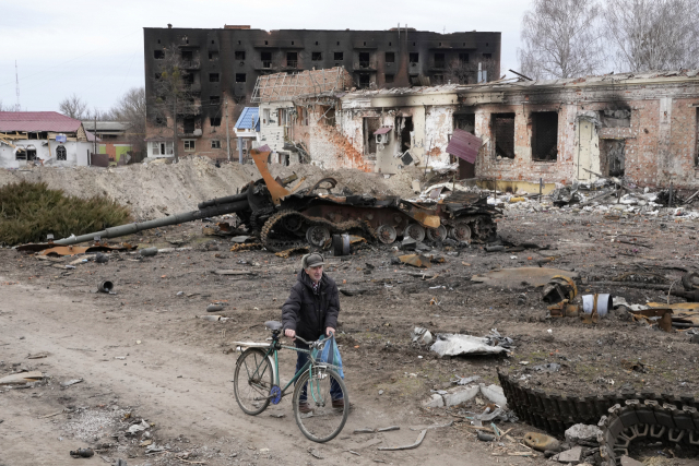 러시아군이 퇴각한 우크라이나 수도 키이우(키예프) 동쪽 약 400㎞ 지점의 트로스얀네츠 마을에서 28일(현지시간) 한 주민이 자전거를 끌며 파괴된 건물과 탱크 앞을 지나가고 있다. /연합뉴스