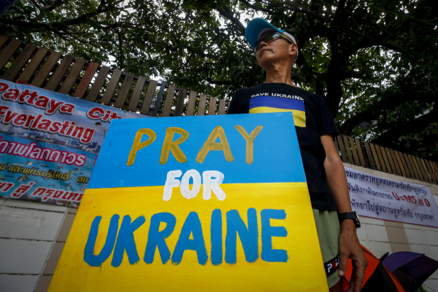 29일(현지시간) 태국 방콕의 러시아 대사관 밖에서 한 시위자가 우크라이나를 지지하는 팻말을 들고 있다. EPA 연합뉴스