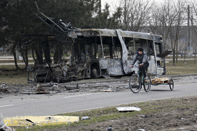 29일(현지 시간) 우크라이나 마리우폴에서 한 여성이 전쟁으로 파괴된 버스 옆을 지나가고 있다. AP연합뉴스