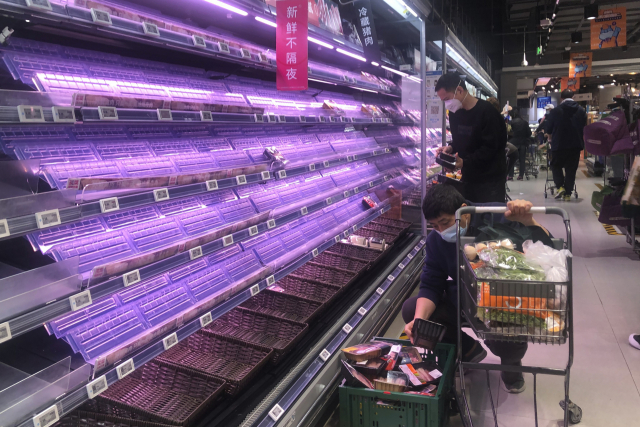 상하이의 한 슈퍼마켓에서 30일 고객들이 빈 진열대를 살펴보고 있다. 동서로 나눠 도시가 봉쇄된 상하이에서는 확진자가 줄어들지 않으면서 도시 전체 봉쇄기간이 늘어날 수 있다는 소문이 확산되면서 시민들이 생필품 사재기에 나서고 있다. AP연합