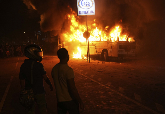 1일(현지시간) 스리랑카 콜롬보 외곽에 있는 스리랑카 대통령 사저 밖에서 시위대가 버스에 불을 지른 후 지켜보고 있다.AP 연합뉴스