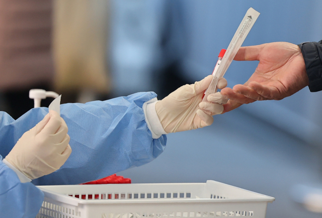 서울 중구 서울역 코로나19 임시선별검사소를 찾은 시민이 PCR 검사 키트를 받고 있다. 연합뉴스