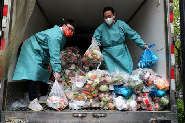 방호복을 착용한 사람들이 5일 중국 상하이에서 트럭에 실린 야채와 식료품을 봉쇄 지역 거주민들에게 나눠주고 있다. 로이터연합