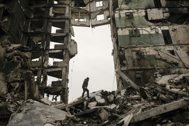 우크라이나 수도 키이우(키예프) 북서쪽 소도시 브로댠카의 한 주민이 5일(현지시간) 러시아군 공격으로 중앙이 뻥 뚫리는 형태로 파괴된 아파트 건물 잔해 속에서 쓸만한 것들을 찾고 있다. AP연합뉴스