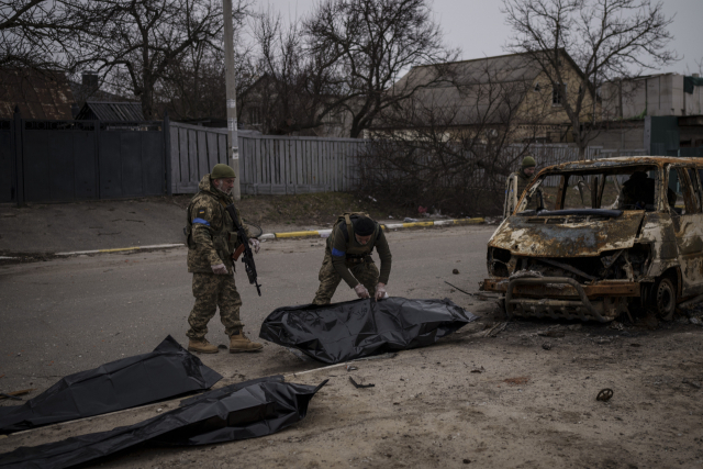 우크라이나 군인들이 5일(현지시간) 수도 키이우(키예프) 외곽 소도시 부차의 거리에서 검게 탄 차 안에 방치된 민간인 시신 4구를 수습하고 있다. /연합뉴스