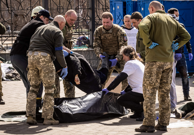 8일 우크라이나 동부 크라마토르스크의 한 기차역이 폭격으로 피해를 입은 가운데 우크라이나 군인들이 시신을 옮기고 있다. AFP연합뉴스