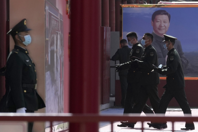 지난달 4일 중국 군 장병들이 베이징에서 시진핑 중국 국가주석의 사진이 전시된 게시판 옆을 지나가고 있다. AP연합뉴스