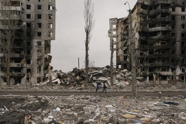 우크라이나 수도 키이우의 북서쪽 소도시인 브로댠카 주민들이 5일(현지 시간) 러시아군의 공격으로 파괴되고 벽면이 검게 그을린 아파트 앞을 걸어가고 있다. AP연합뉴스