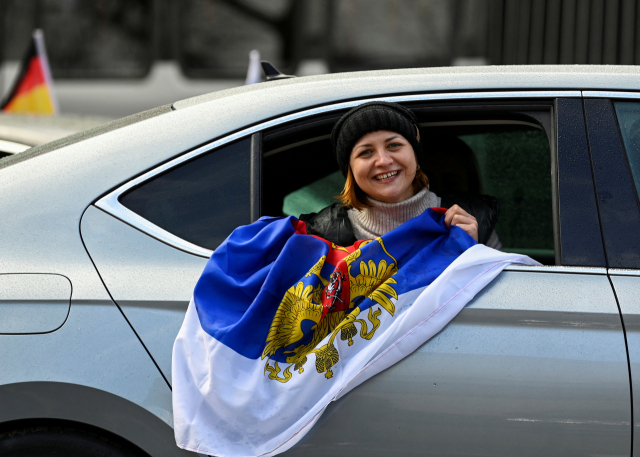 독일 하노버에서 10일(현지 시간) 진행된 친러시아 시위에서 한 여성이 러시아 국기를 차 밖으로 꺼내보이며 미소짓고 있다. 로이터연합뉴스