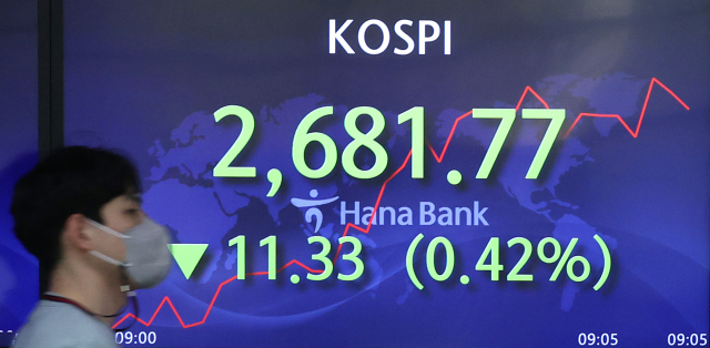 12일 오전 서울 중구 하나은행 본점 딜링룸에서 직원이 전광판 앞을 지나고 있다. 연합뉴스