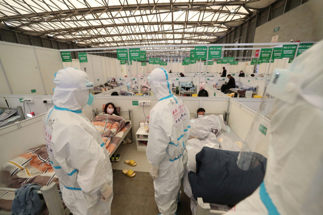 코로나19 감염자 임시 격리시설로 바뀐 중국 상하이의 신국제전람회장에서 9일 방호복을 입은 의료진이 환자 상태를 체크하고 있다. 연합뉴스