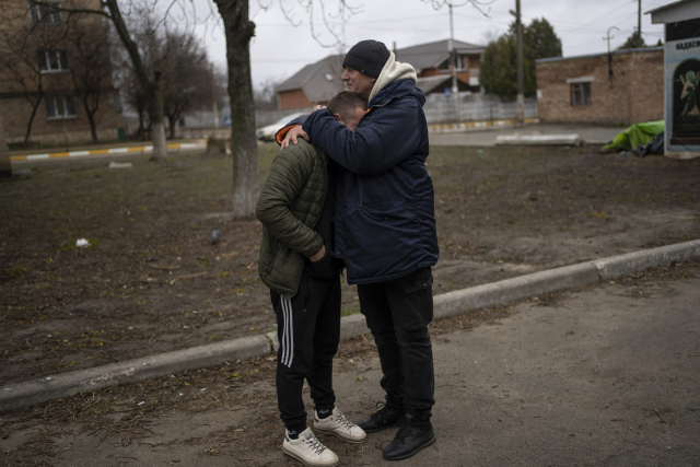 한 우크라이나 남성(왼쪽)이 13일(현지 시간) 부차에서 친구 아버지의 품에 안겨 슬퍼하고 있다. 이 남성의 친구는 이르핀으로 피란을 가다가 러시아군에 의해 사살됐다. AP연합뉴스