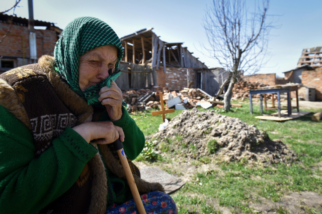 우크라이나 수도 키이우(키예프) 북쪽 외곽에서 14일(현지시간) 한 여성이 집 마당에 묻은 딸의 무덤 앞에서 오열하고 있다. 이 여성의 딸은 러시아군의 공습 때 희생됐다. EPA연합뉴스