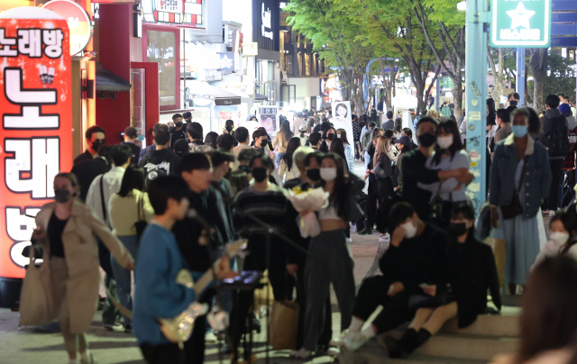 코로나19 사회적 거리두기 해제를 하루 앞둔 17일 오후 서울 마포구 홍대입구역 인근에서 시민들이 버스킹 공연을 관람하고 있다. 연합뉴스