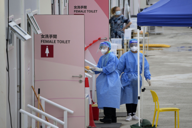 지난 3월 26일(현지시간) 홍콩의 신종 코로나바이러스 감염증(코로나19) 환자 임시 격리 시설에서 보호복을 차용한 직원들이 화장실 앞에 서 있다. AP 연합뉴스