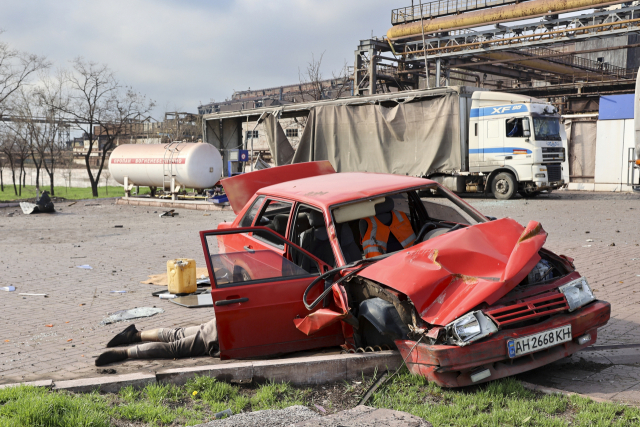 16일(현지시간) 우크라이나 마리우폴에서 한 민간인의 시신이 훼손된 차 옆에 놓여 있다. AP 연합뉴스