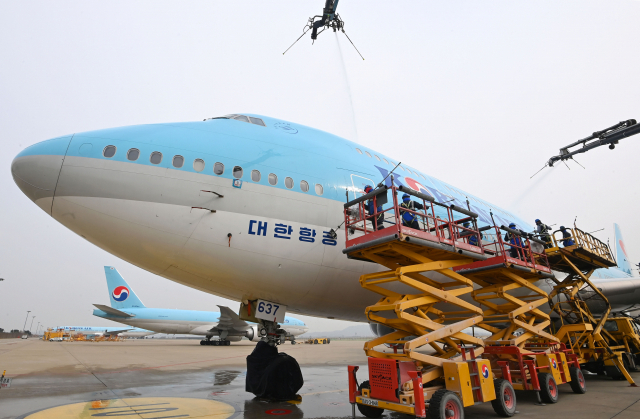 사회적 거리두기 전면 해제 첫날인 18일 오전 영종도 인천국제공항 대한항공 정비 격납고에서 관계자들이 보잉 747-8i 항공기 동체를 세척하고 있다. 이날 묵은 때를 벗고 새 단장을 한 항공기는 장거리 노선에 투입되는 보잉747-8i로 동체, 날개뿐 아니라 엔진 내부 구석구석까지 먼지와 이물질을 말끔히 제거했다. 동체를 포함한 항공기 외부 세척에는 26m까지 상승하는 차량 탑재형 고소 작업대 1대, 중대형 리프트카 3대, 물탱크 차량 3대가 투입됐다./영종도=권욱 기자 2022.04.18