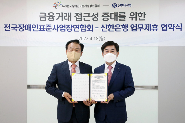 정용기(오른쪽) 신한은행 개인그룹 부행장과 김남기 전국장애인표준사업장연합회 회장이 18일 서울 영등포구 신한은행 강서본부에서 업무협약을 맺고 기념촬영을 하고 있다. 사진 제공=신한은행