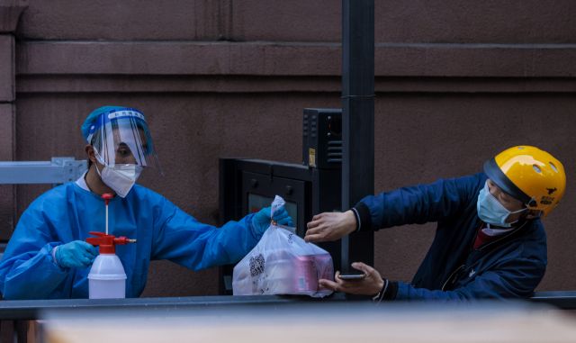 중국 상하이에서 18일 배달원이 코로나19 확산 방지를 위해 봉쇄 조처가 내려진 주거단지의 보안요원에게 음식을 전달하고 있다. EPA연합뉴스