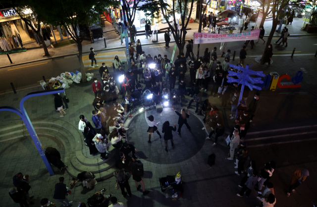 코로나19 사회적 거리두기 해제를 하루 앞둔 17일 오후 서울 마포구 홍대입구역 인근에서 시민들이 버스킹 공연을 관람하고 있다./연합뉴스