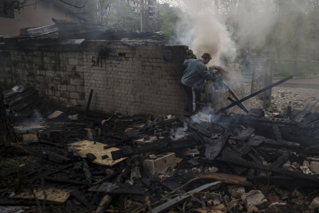 우크라이나 북동부 지역 카르키우 지역에서 한 거주민이 러시아의 폭격 이후 불타고 있는 건물에서 불을 끄고 있다. AP연합뉴스
