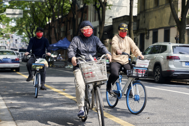 21일(현지시간) 중국 상하이에서 시민들이 자전거에 식료품과 생필품을 싣고 이동하고 있다. AP연합뉴스