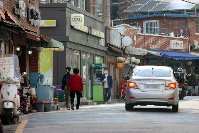 이면도로 등에서 보행자의 통행 권리를 대폭 향상한 개정 도로교통법과 하위법령이 20일부터 시행된다. 이에 따라 보도와 차도가 구분되지 않고 중앙선이 없는 도로에서 보행자의 옆을 지나는 운전자는 안전한 거리를 두고 서행해야 하며, 보행자의 통행에 방해될 때는 서행하거나 우선 멈춰 보행자가 안전하게 통행할 수 있게 해야 한다. 위반시에는 범칙금이 부과된다. 사진은 18일 오후 서울 종로구 성균관대 인근의 한 이면도로. /연합뉴스