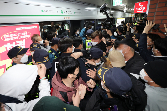 21일 오전 서울 지하철 2호선 시청역에서 열린 전국장애인차별철폐연대(전장연)의 출근길 지하철 탑승 시위로 열차가 오래 지연되자 경찰이 전장연 회원들을 열차에서 끌어내려고 시도하고 있다. 연합뉴스