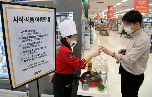 코로나19 확산에 따른 사회적 거리 두기가 전면 해제된 가운데 25일 서울 용산구의 한 대형 마트를 찾은 고객이 시식 코너에서 판촉용 음식을 시식하고 있다. 권욱 기자