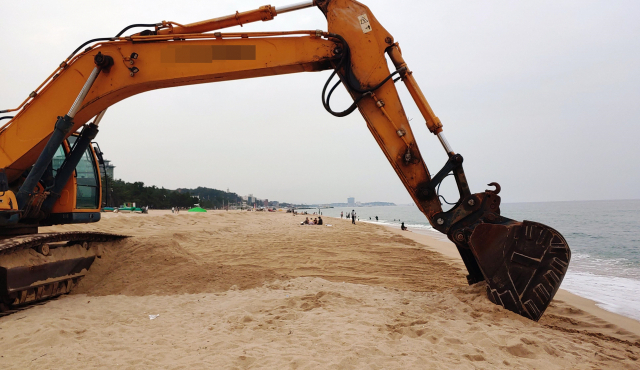 한 굴착기가 해변에 있는 모래를 파고 있다. 연합뉴스