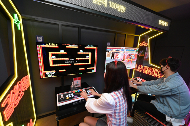 LG전자 모델들이 부산 광안리의 금성오락실에서 올레드 TV로 게임을 즐기고 있다. 사진제공=LG전자