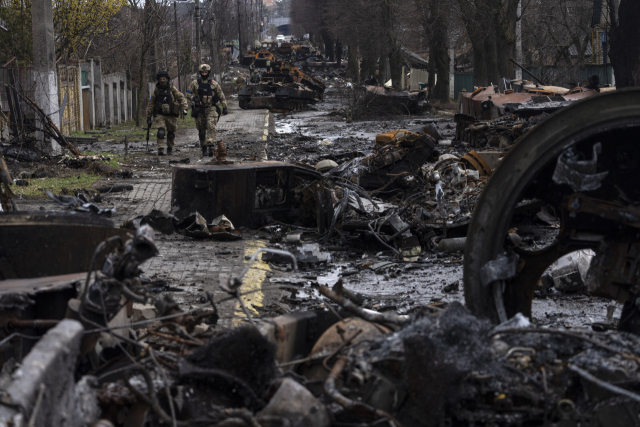 우크라이나 수도 키이우 외곽 소도시 부차에서 지난 3일(현지시간) 우크라이나 군인들이 파괴된 러시아군 탱크 잔해가 널려 있는 거리를 지나가고 있다. AP 연합뉴스