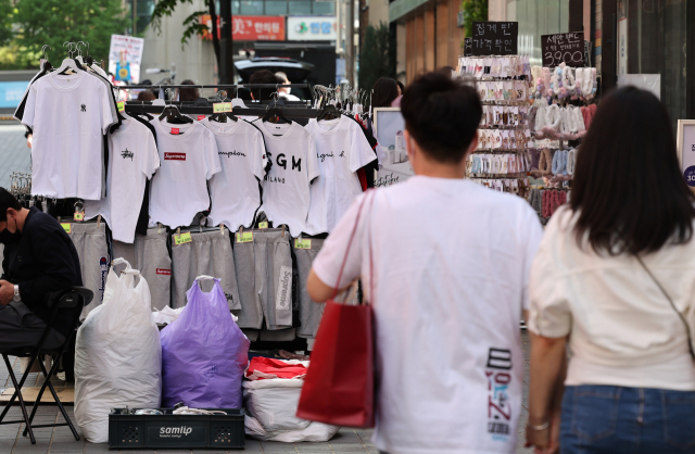 서울 낮 기온이 23도까지 오르며 초여름 날씨를 보인 지난 27일 오후 서울 중구 명동에서 반소매 옷차림을 한 시민들이 반소매 옷 판매대 앞을 지나고 있다. 연합뉴스