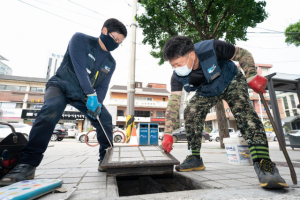 서울시설공단 직원들이 보도블록 아래에 설치된 수도 계량기를 디지털 수도 계량기로 교체하기 위해 계량기 덮개를 열고 있다. 사진 제공=서울시설공단