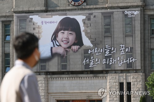 한 시민이 2일 서울 중구 서울도서관 외벽에 설치된 어린이날 100주년 기념 꿈새김판을 보고 있다. 연합뉴스