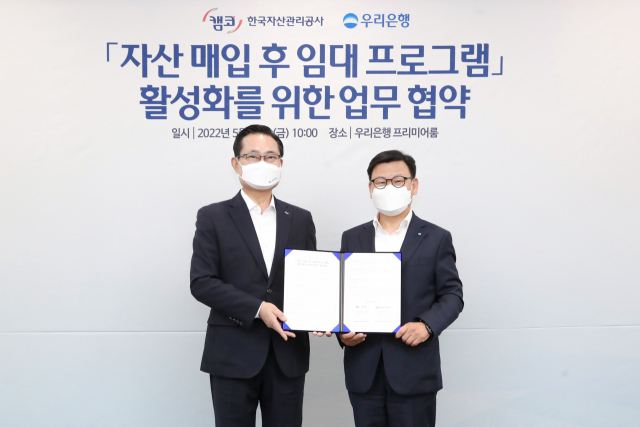 이원덕(오른쪽) 우리은행장과 권남주 한국자산관리공사 사장이 13일 서울 중구 우리은행 본점에서 열린 ‘자산 매입 후 임대프로그램 활성화를 위한 업무협약’을 체결한 뒤 기념촬영 하고 있다. 사진제공=우리은행