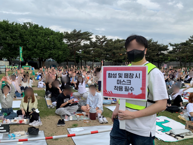 13일 오후 서울 송파구 올림픽공원 88잔디마당에서 대규모 야외 대중음악 축제 ‘뷰티풀 민트 라이프 2022’가 열린 가운데 돗자리 위에 앉은 시민들 사이로 “함성 및 떼창 시 마스크 착용 필수” 안내 피켓을 든 직원이 지나가고 있다. 김남명 기자