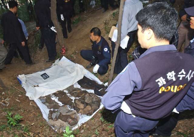 지난 2002년 9월 개구리소년들의 것으로 추정되는 유골이 발견된 현장에서 경찰관들이 옷가지들을 살펴보고 있다. /연합뉴스