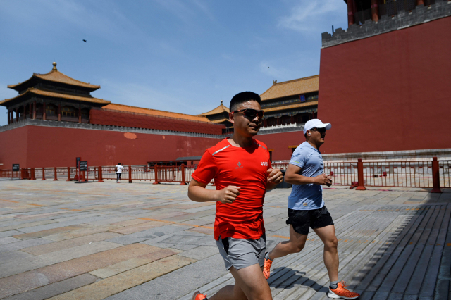 마스크를 착용하지 않은 두 남성이 17일 중국 베이징의 자금성 주위를 달리고 있다. 베이징 당국은 관내 코로나19 오미크론 변이가 유행하자 자금성을 폐쇄했다. AFP연합뉴스
