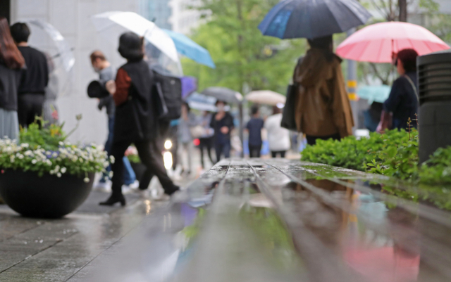소나기가 내린 18일 오전 서울 종로구 광화문역 인근에서 출근길 시민들이 우산을 쓰고 걸어가고 있다. 연합뉴스
