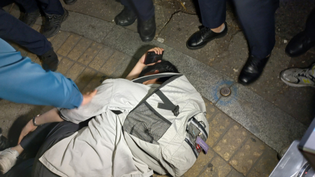 대학생진보연합 일원이 20일 오후 8시 50분께 서울 용산구 하얏트호텔 인근에서 사전에 신고되지 않은 집회를 개최하려다 경찰에 제압당해 쓰러져 있다. 이건율 기자