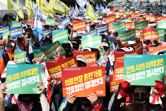 22일 오후 서울 여의대로에서 열린 '간호법 제정 저지를 위한 공동 궐기대회’에서 대한의사협회 및 대한간호조무사협회원들이 관련 피켓을 들고 있다. 연합뉴스