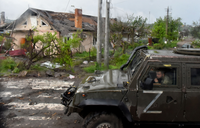 지난 18일(현지시간) 러시아군이 점령한 우크라이나 마리우폴에서 'Z 표식'을 한 러시아군 차량이 무너진 민가를 지나쳐 달리고 있다. AFP 연합뉴스